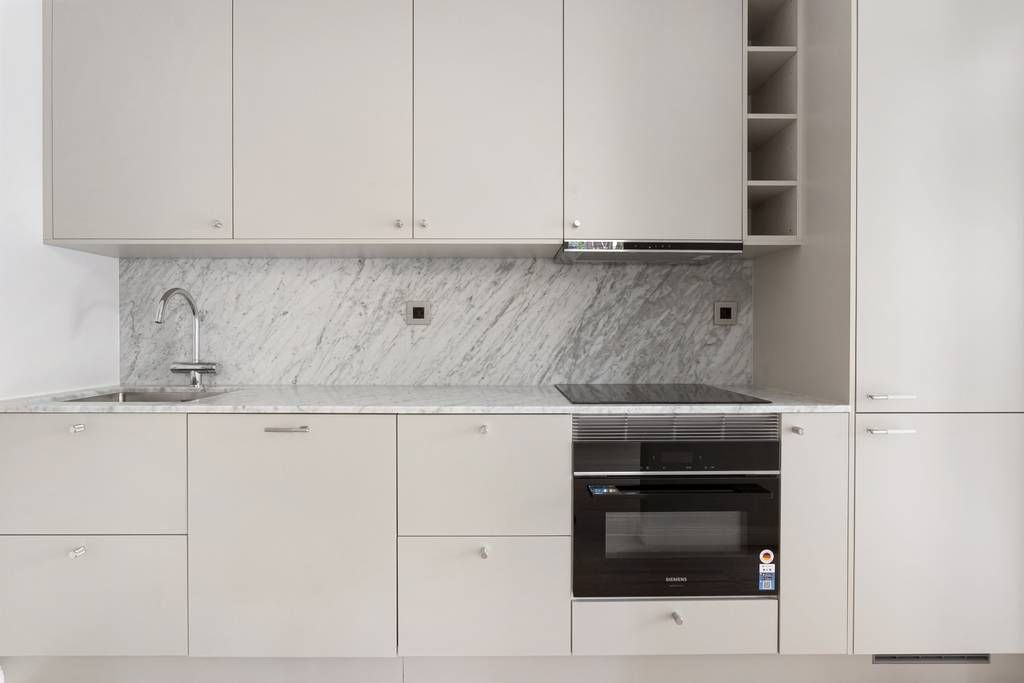 Kökets inredning med vita luckor, bänkskiva i marmor samt integrerad ugn och spishäll.