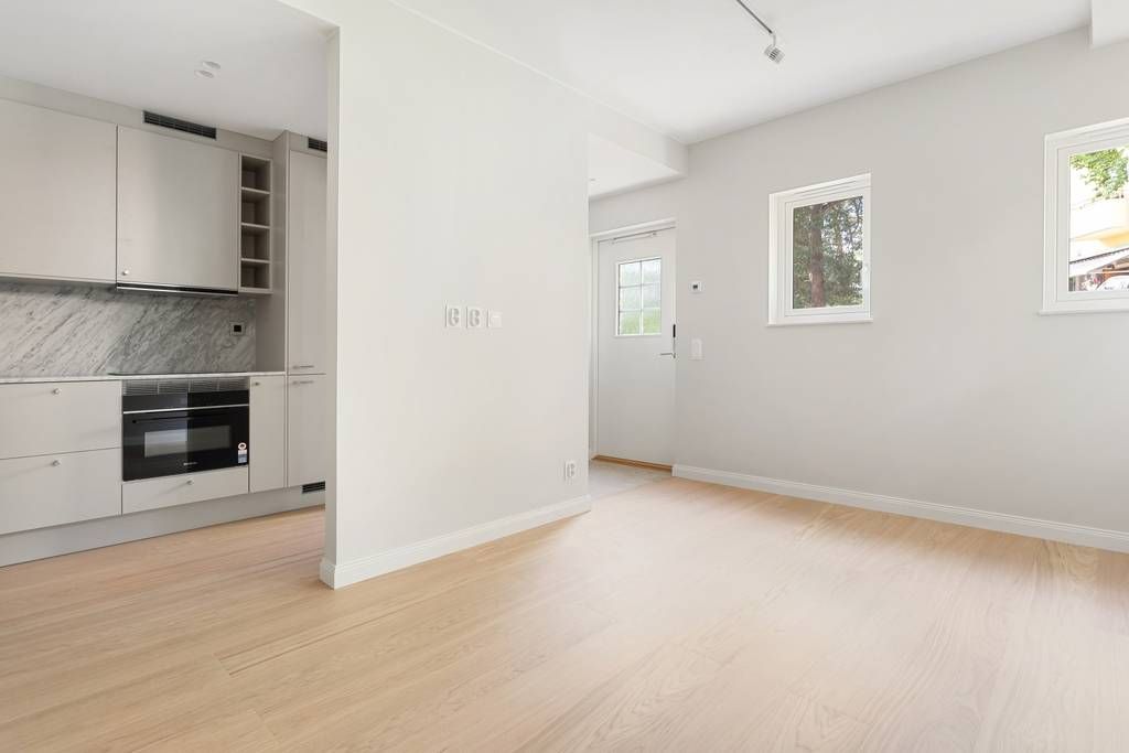 Öppen planlösning i Klappträet 6 som visar köket och allrummet med ett ljust trägolv.