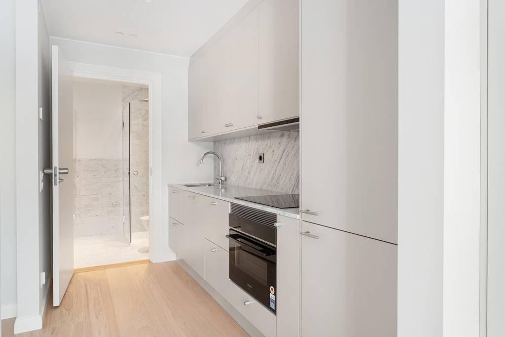 Vy in mot det moderna köket från allrummet, med fokus på de integrerade vitvarorna.