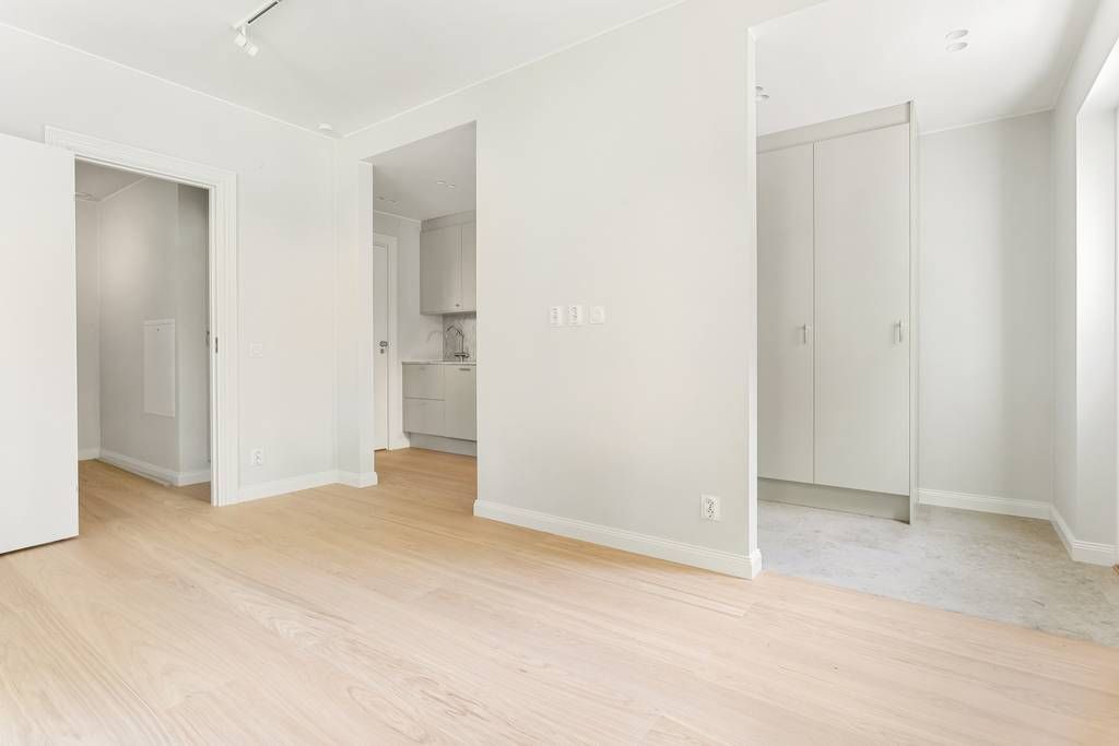 Stort och ljust allrum med vitmålade väggar och ett genomgående golv i ekparkett.