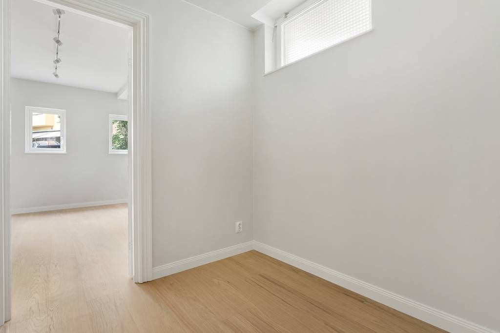 Hörn av ett rum med ekparkett och en stor spegel som skapar en känsla av rymd.